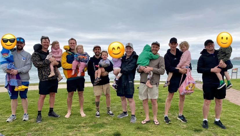 A group of dads and their kids together outdoors.